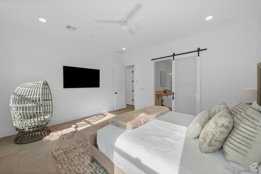 Bedroom with connected bathroom, a barn door, and tile patterned flooring