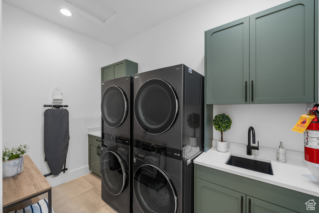 Washroom with stacked washer and dryer, cabinets, light tile patterned floors, and sink