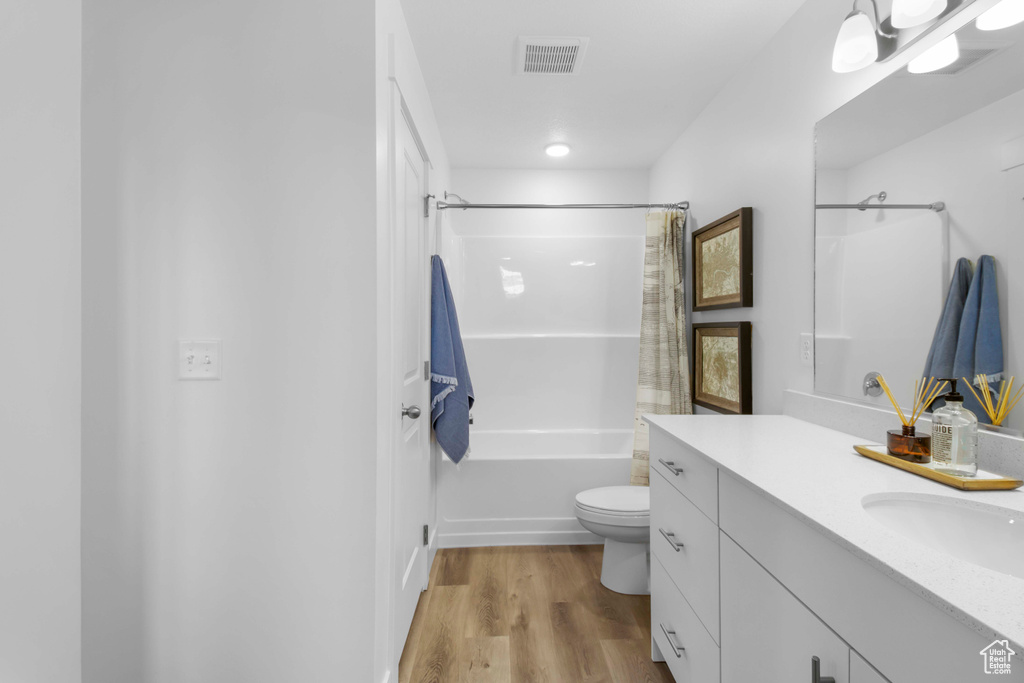 Full bathroom featuring shower / bath combination with curtain, hardwood / wood-style flooring, vanity, and toilet