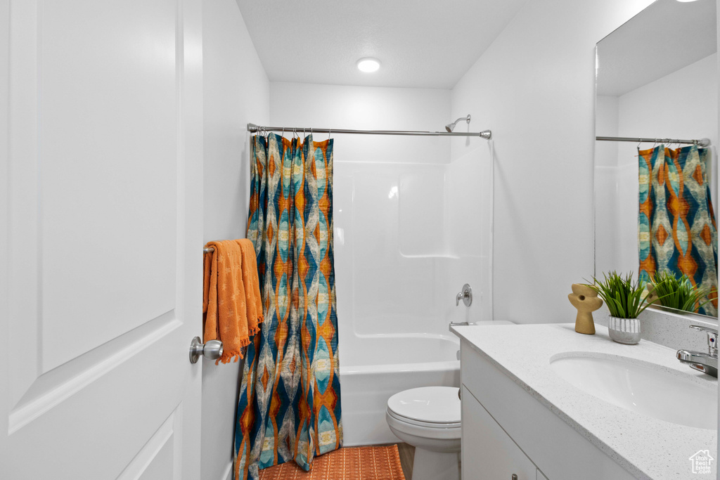 Full bathroom featuring toilet, vanity, and shower / bathtub combination with curtain