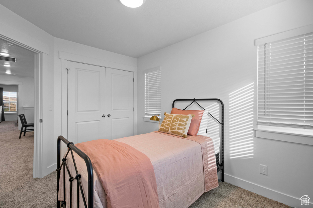 Bedroom with light colored carpet and a closet