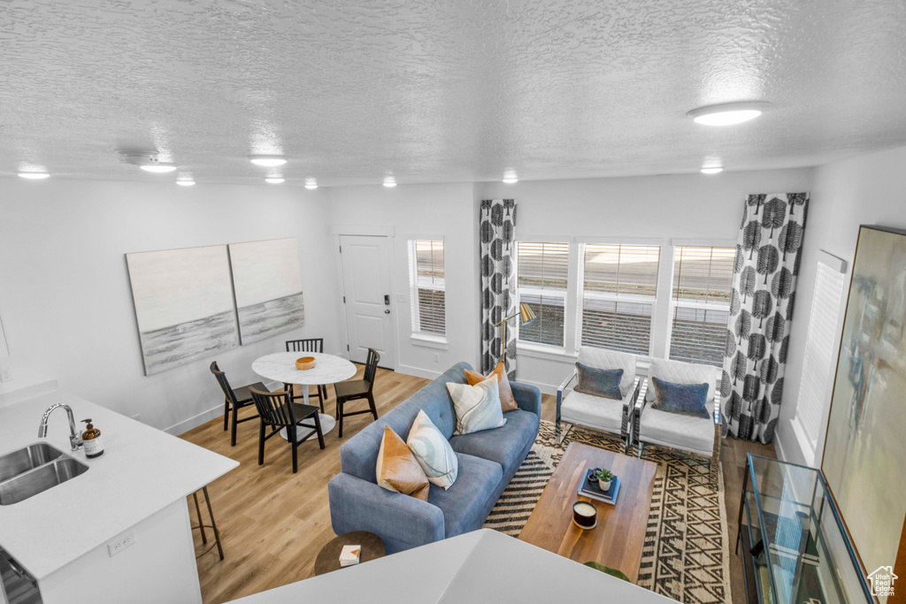 Living room with a textured ceiling, light hardwood / wood-style flooring, and sink