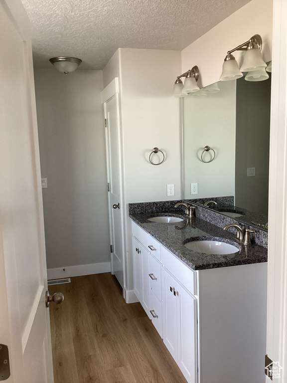 Bathroom featuring hardwood / wood-style flooring, vanity, and a textured ceiling