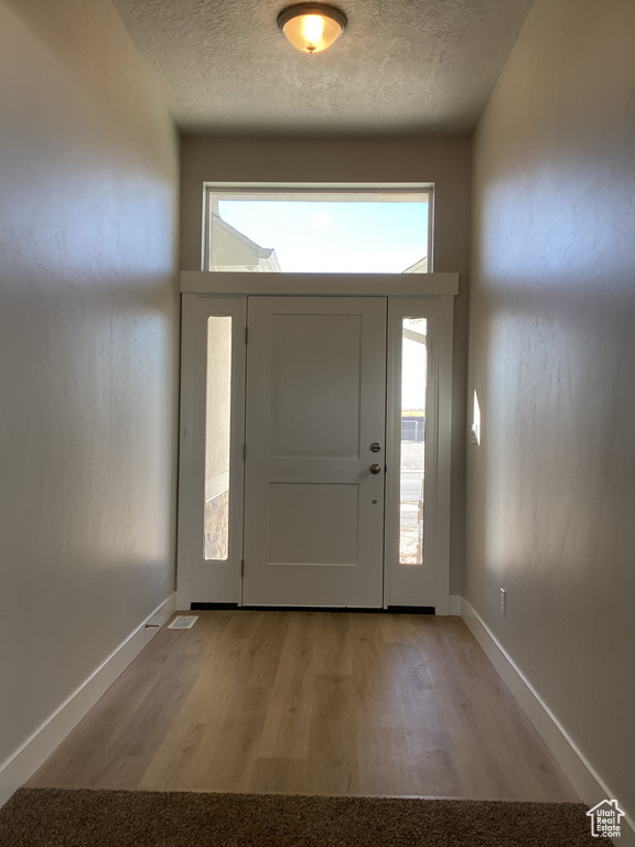 Entrance foyer with light hardwood / wood-style floors and a textured ceiling