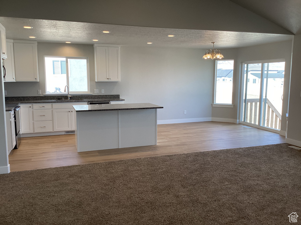 Kitchen featuring light hardwood / wood-style floors, white cabinets, sink, and a center island