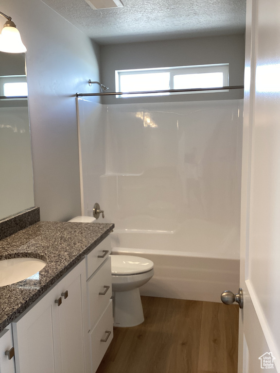Full bathroom with bathing tub / shower combination, hardwood / wood-style floors, vanity, and toilet