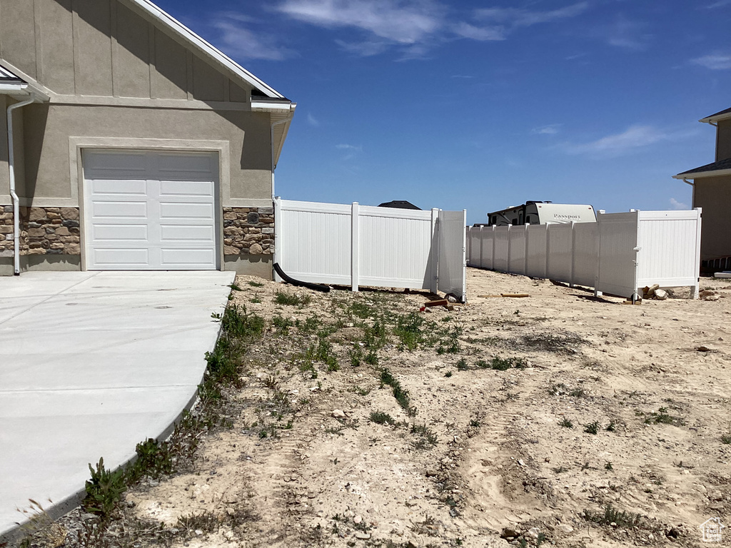 View of yard with concrete driveway and a garage