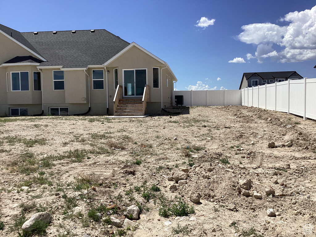 Rear view of property featuring a fenced backyard, stucco siding, and cooling unit