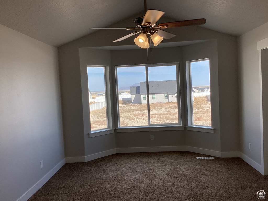 Carpeted empty room with ceiling fan, a textured ceiling, and vaulted ceiling