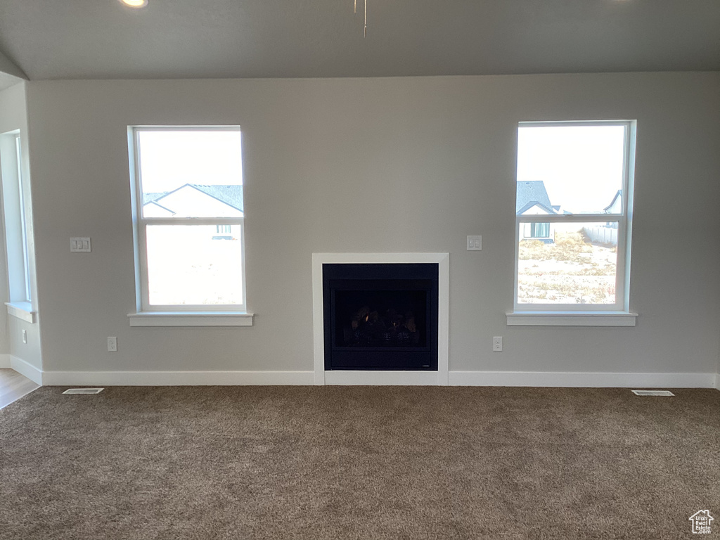 Unfurnished living room featuring a healthy amount of sunlight and carpet