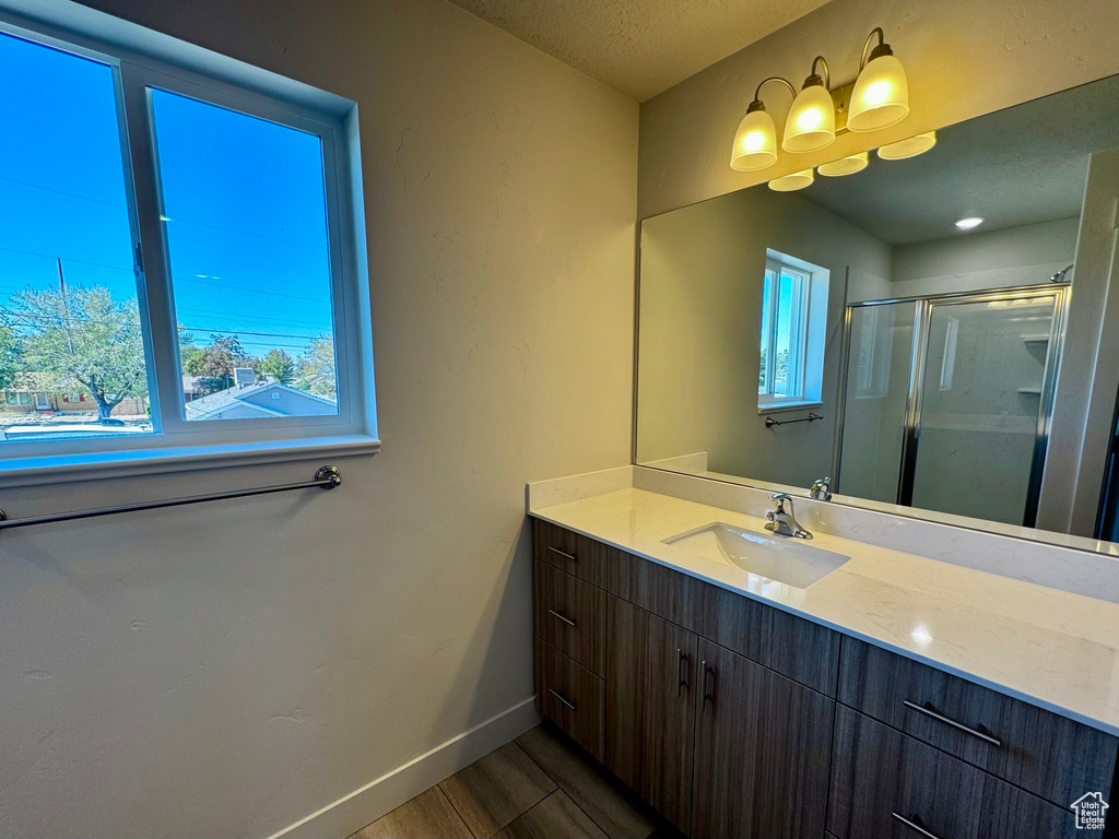 Bathroom with hardwood / wood-style floors, walk in shower, vanity, and a textured ceiling