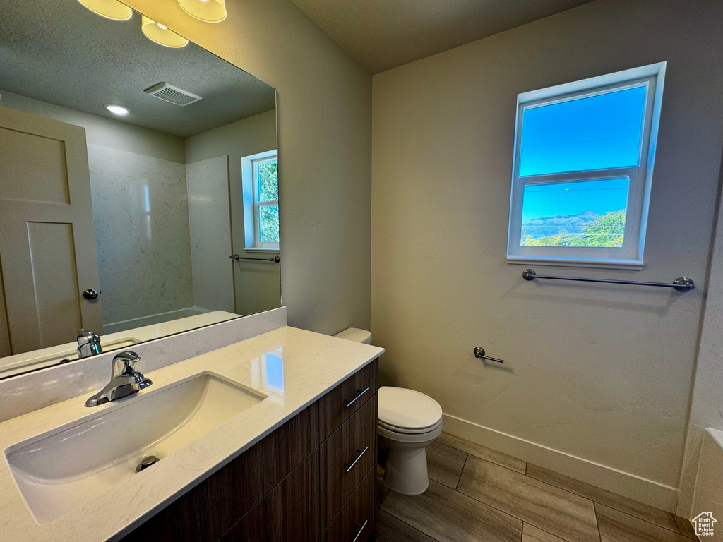 Bathroom featuring vanity, toilet, a shower, and a textured ceiling