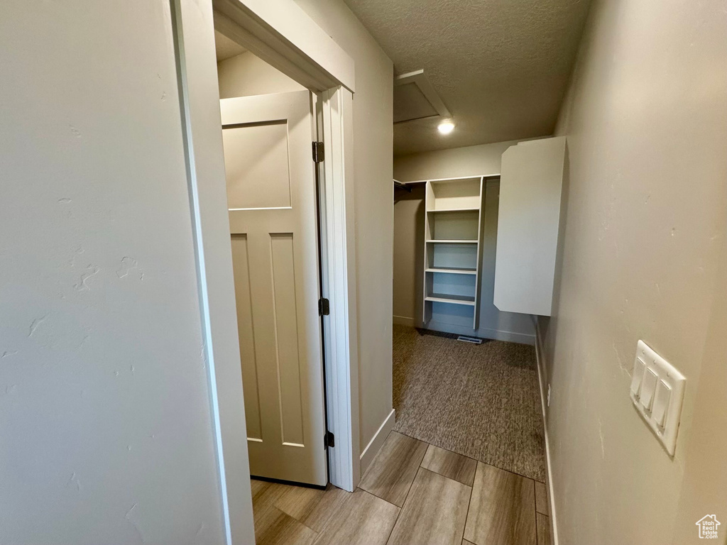 Hall with a textured ceiling and light hardwood / wood-style floors