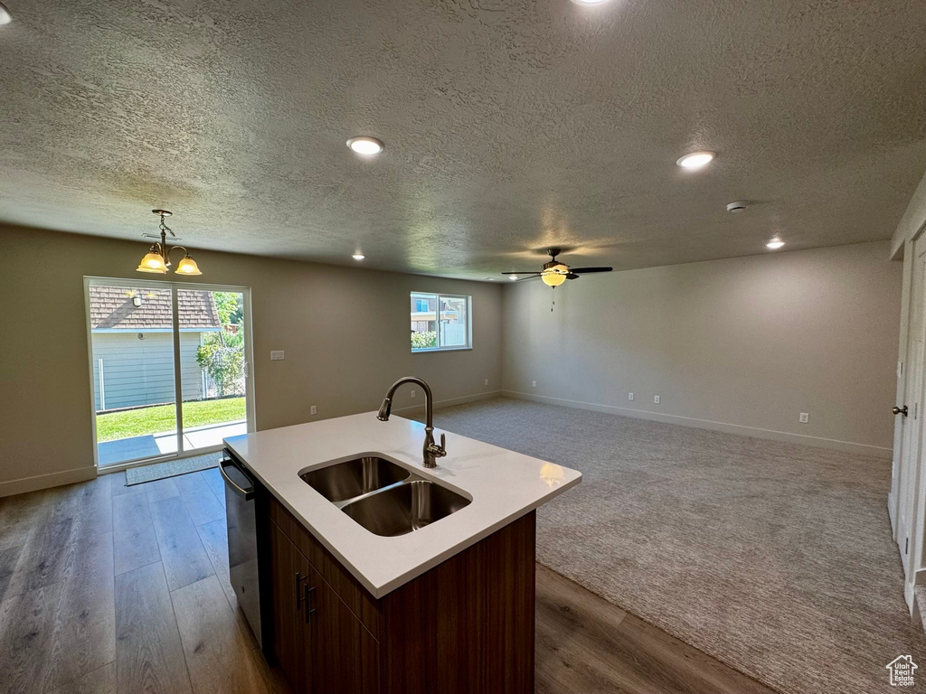 Kitchen featuring hardwood / wood-style flooring, a kitchen island with sink, sink, and decorative light fixtures