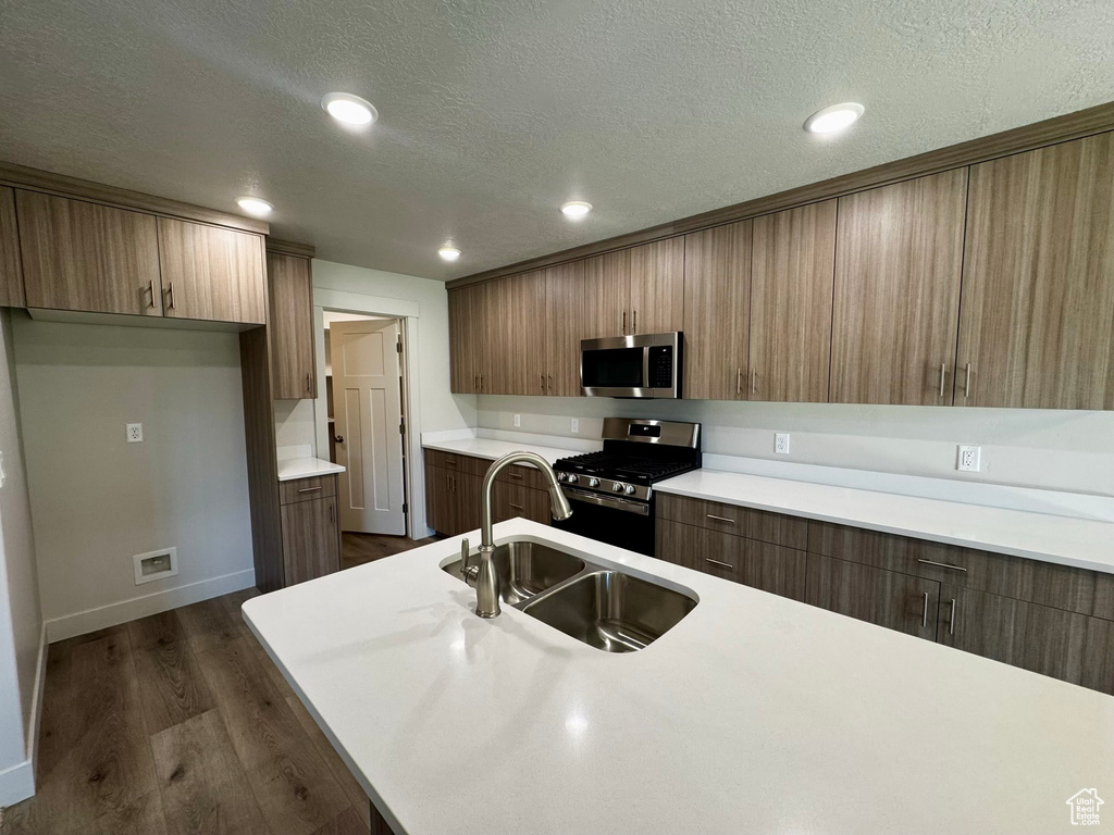 Kitchen featuring stainless steel appliances, dark wood-type flooring, sink, and a textured ceiling