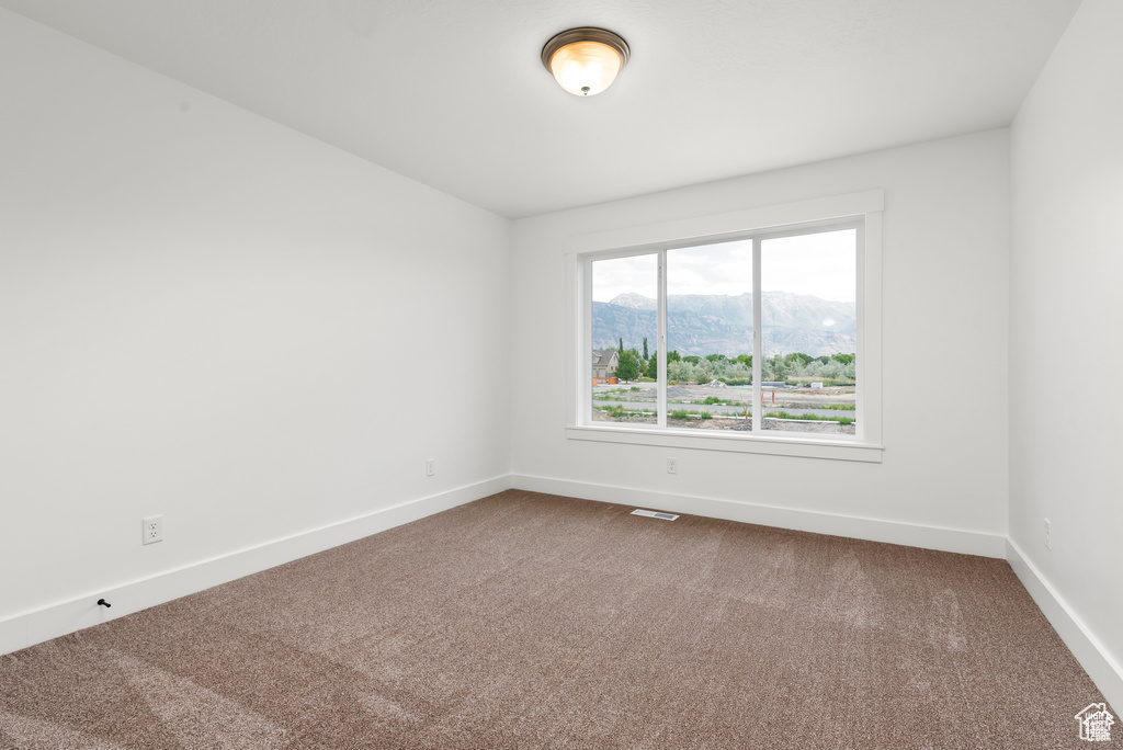 Carpeted spare room featuring a mountain view