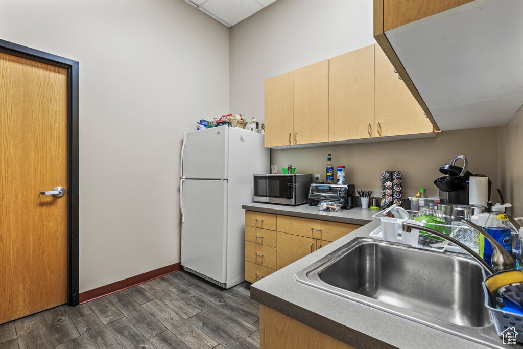 Kitchen with light brown cabinets, white refrigerator, dark hardwood / wood-style floors, and sink