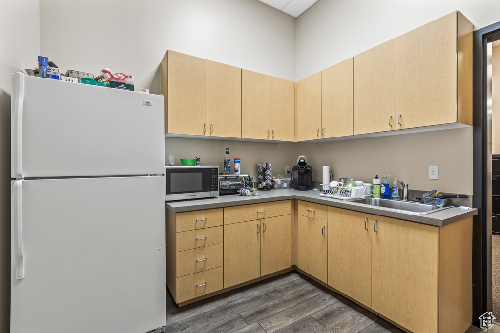 Kitchen featuring dark hardwood / wood-style floors, white refrigerator, sink, and light brown cabinets