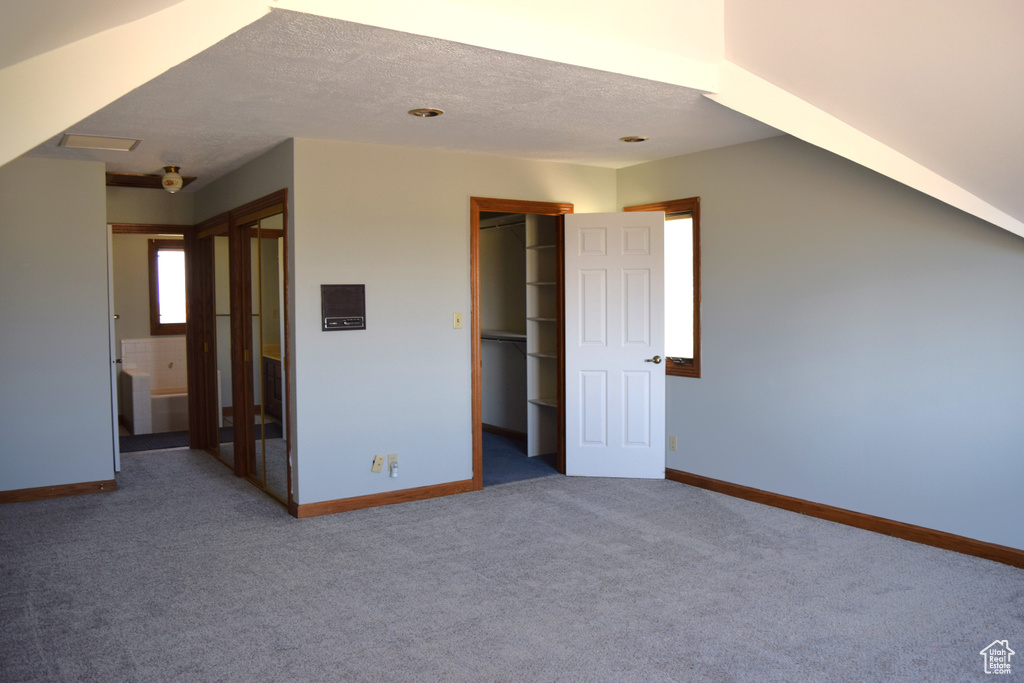 Unfurnished bedroom featuring a spacious closet, carpet flooring, and ensuite bathroom