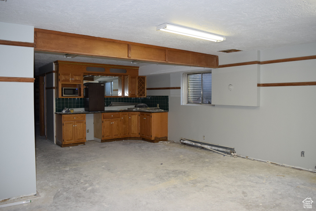 Kitchen with stainless steel microwave, backsplash, and a textured ceiling