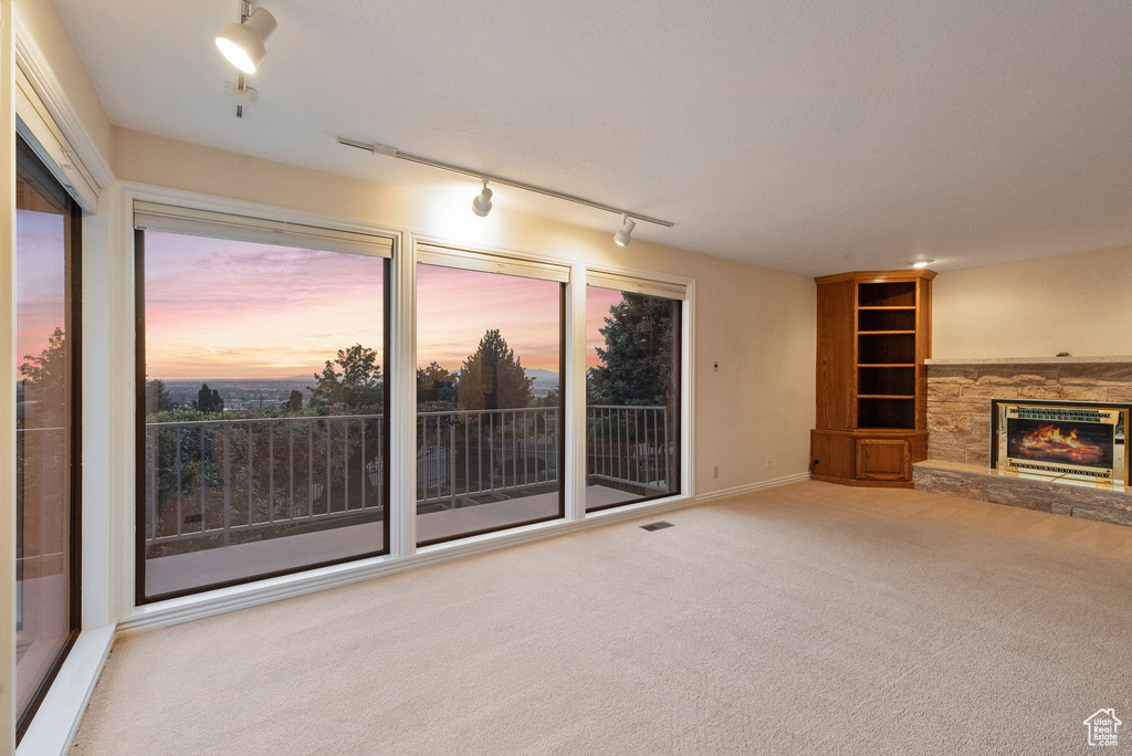 Unfurnished living room with carpet floors, a fireplace, and rail lighting