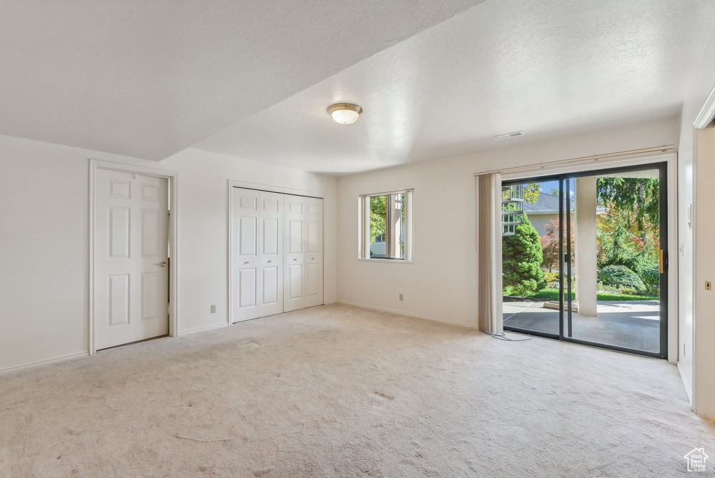 Unfurnished bedroom featuring access to outside, a closet, a textured ceiling, and light carpet