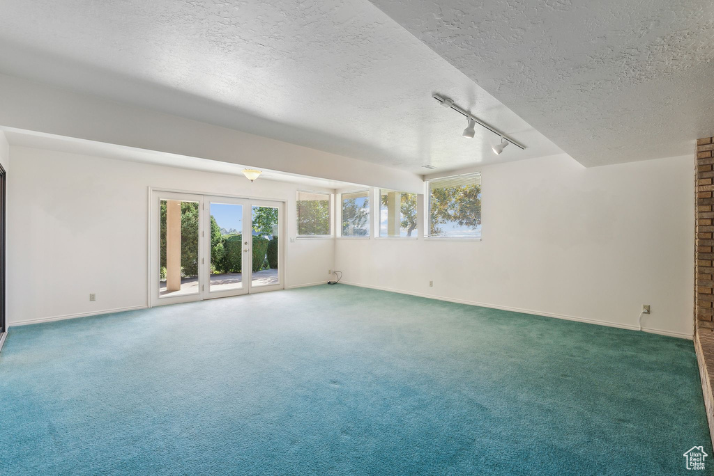 Carpeted spare room with rail lighting and a textured ceiling