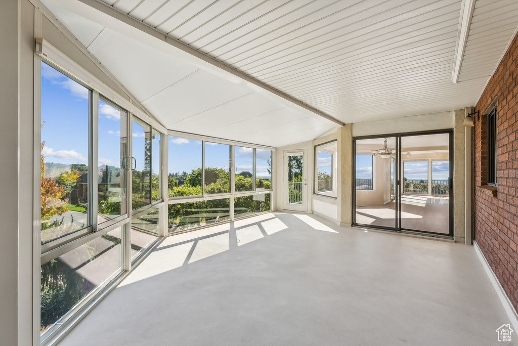 Unfurnished sunroom featuring lofted ceiling with beams