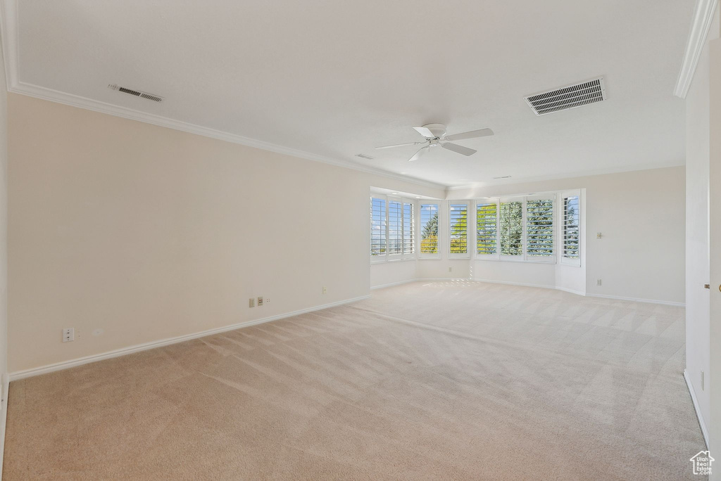 Unfurnished room featuring ornamental molding, ceiling fan, and light colored carpet