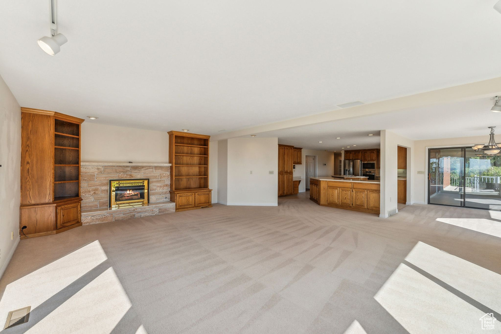 Unfurnished living room featuring light colored carpet and a fireplace