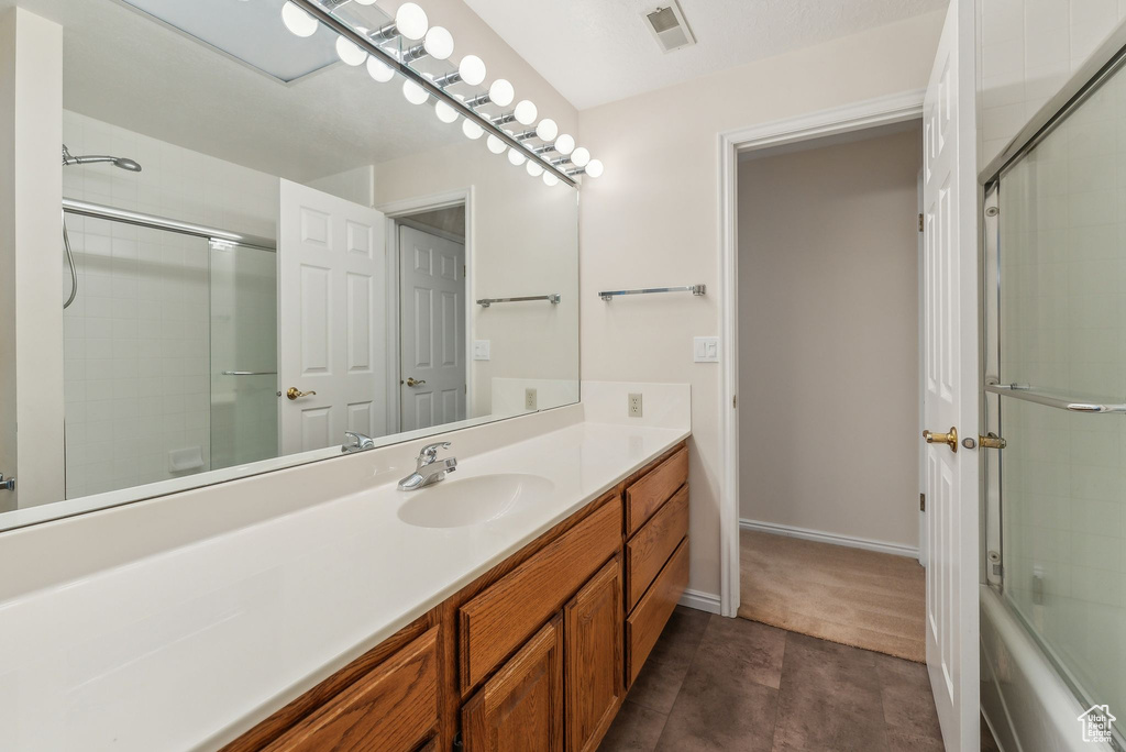 Bathroom featuring shower / bath combination with glass door and vanity