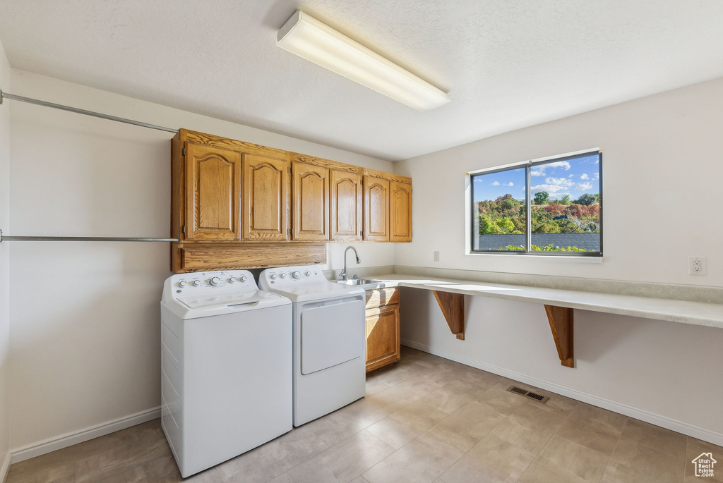 Laundry room with cabinets, sink, and washing machine and clothes dryer