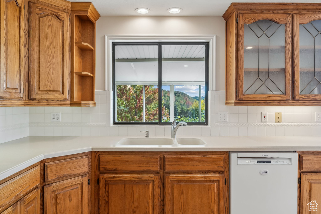 Kitchen featuring white dishwasher, sink, and decorative backsplash