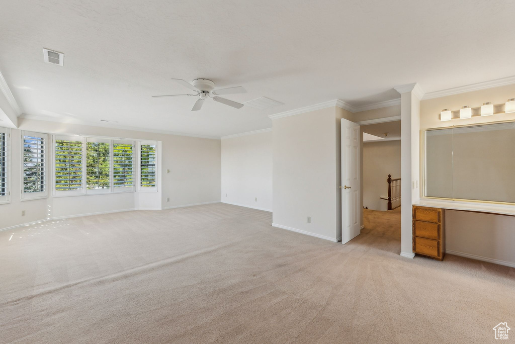 Carpeted spare room with crown molding and ceiling fan