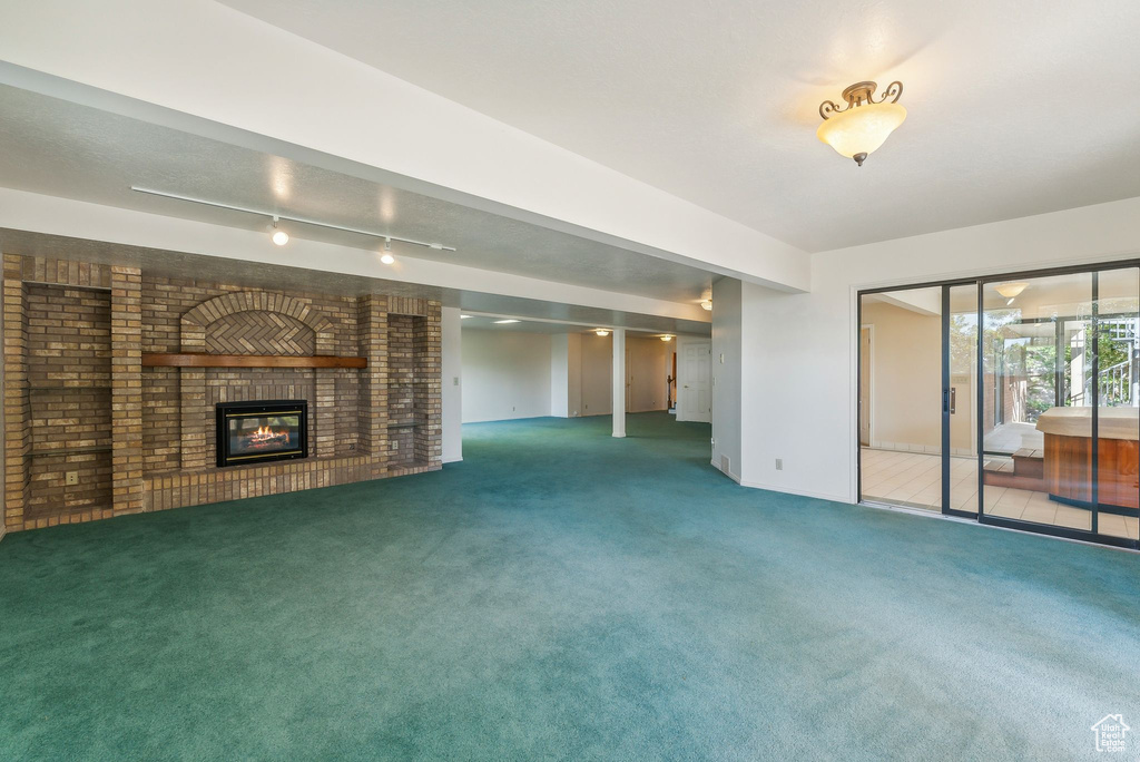 Unfurnished living room with a fireplace, carpet, and track lighting