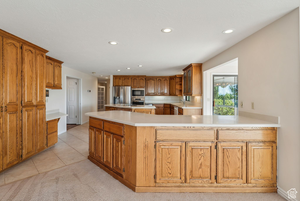 Kitchen featuring light tile patterned floors, sink, stainless steel appliances, and kitchen peninsula