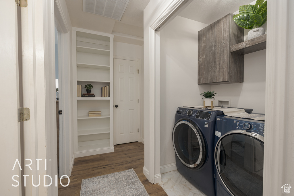 Clothes washing area featuring cabinets, washer and dryer, and dark hardwood / wood-style flooring