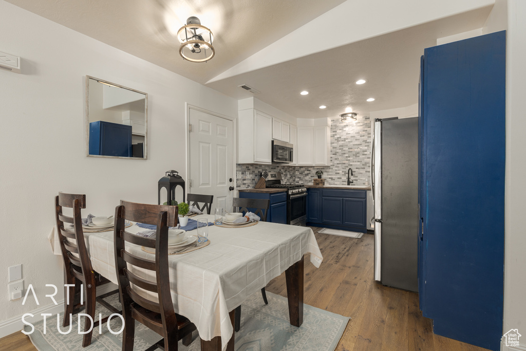 Dining area featuring sink, vaulted ceiling, and hardwood / wood-style floors