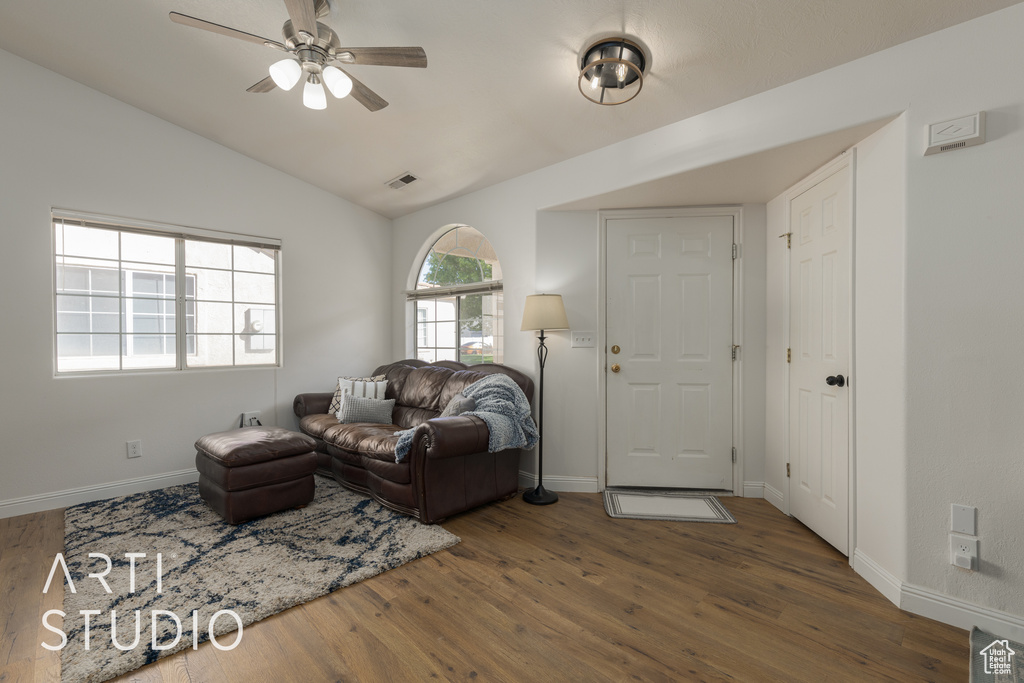 Living room featuring ceiling fan, dark hardwood / wood-style floors, and vaulted ceiling