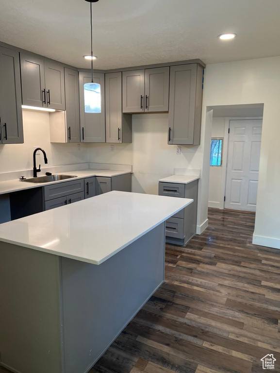 Kitchen with gray cabinets, pendant lighting, dark wood-type flooring, and sink