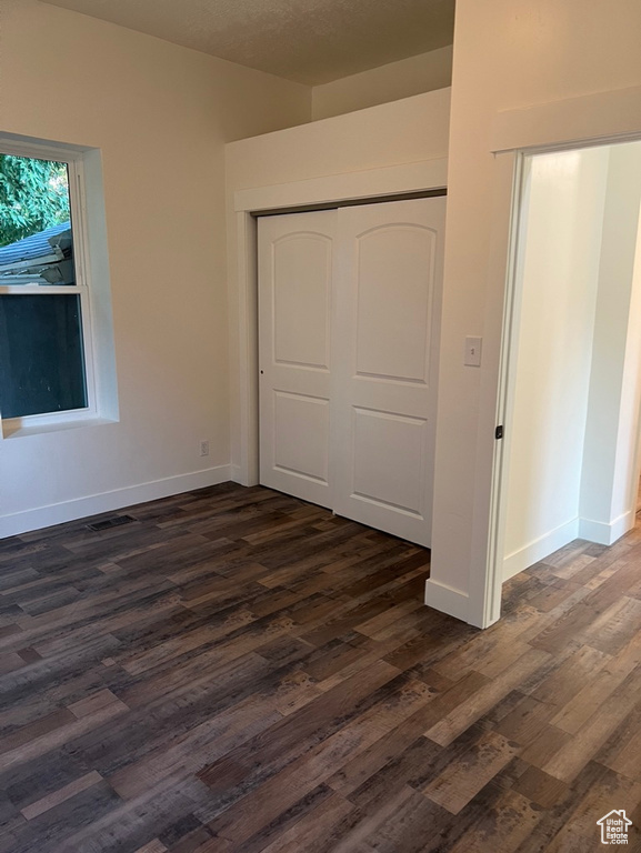 Unfurnished bedroom featuring a textured ceiling, a closet, and dark hardwood / wood-style floors