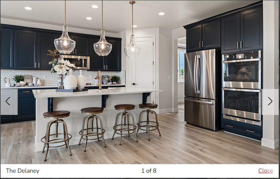 Kitchen featuring light hardwood / wood-style flooring, a kitchen breakfast bar, stainless steel appliances, hanging light fixtures, and an island with sink