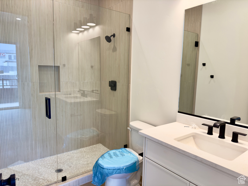 Bathroom featuring an enclosed shower, vanity, and toilet