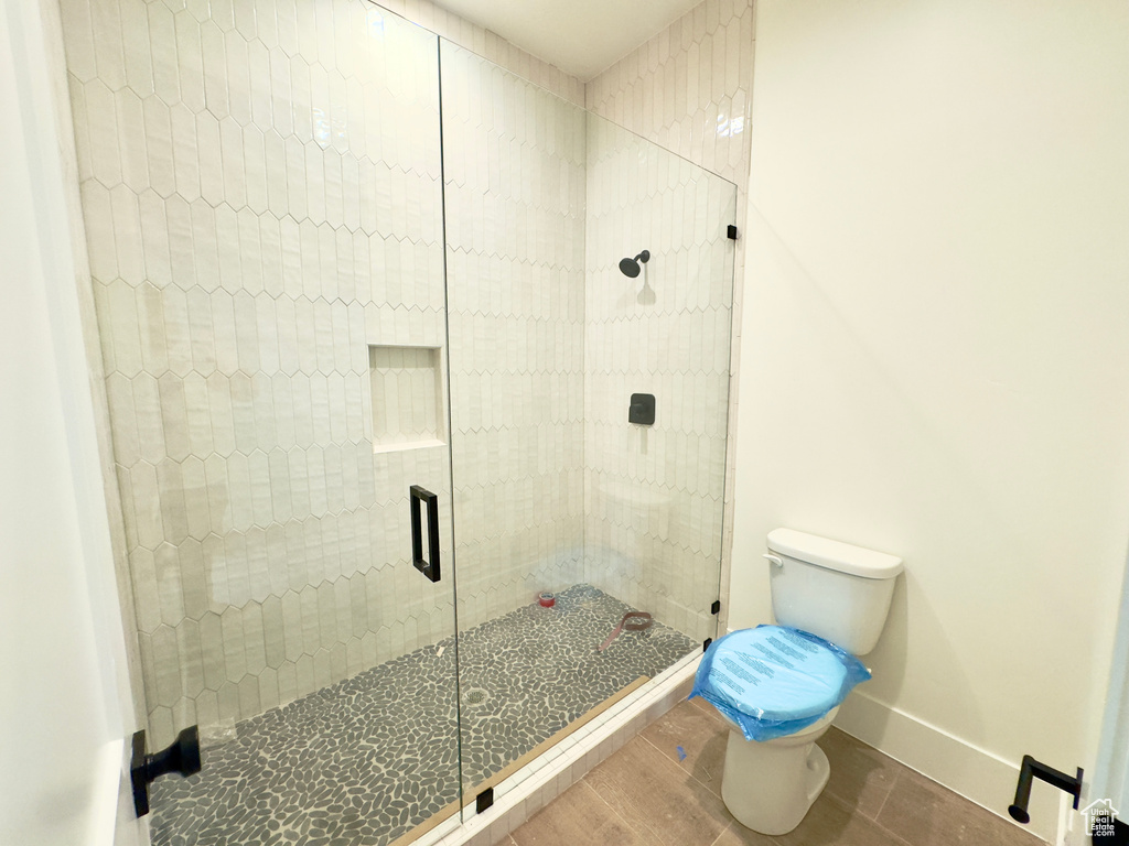 Bathroom featuring wood-type flooring, a shower with door, and toilet