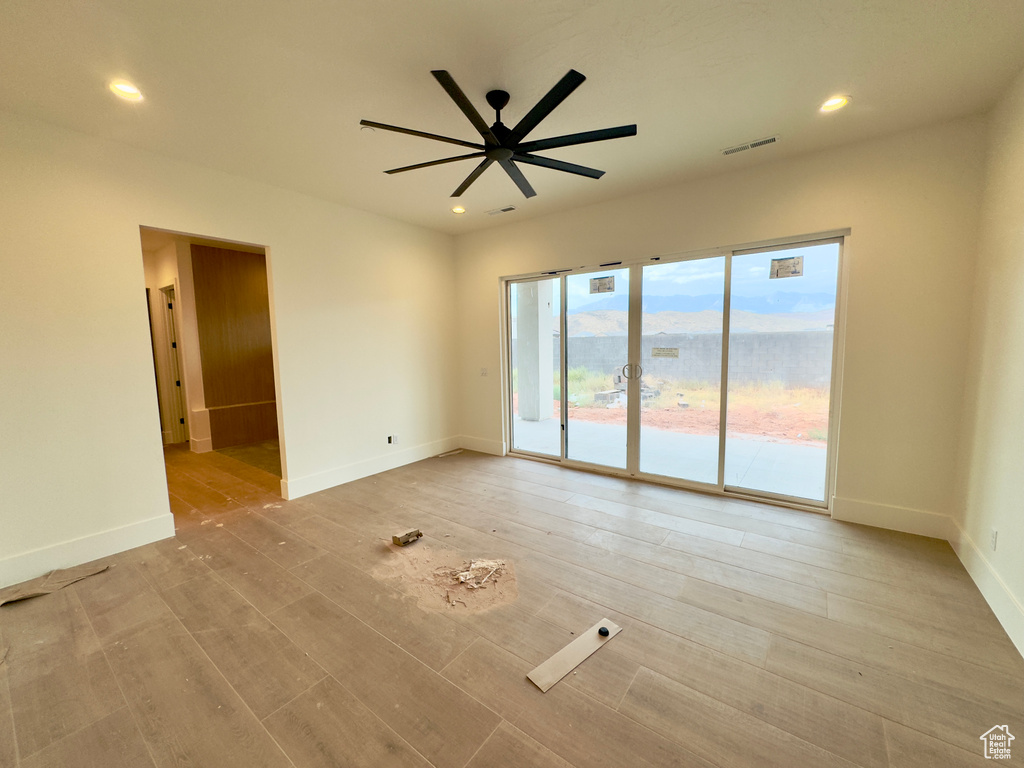 Spare room featuring light wood-type flooring, a mountain view, and ceiling fan