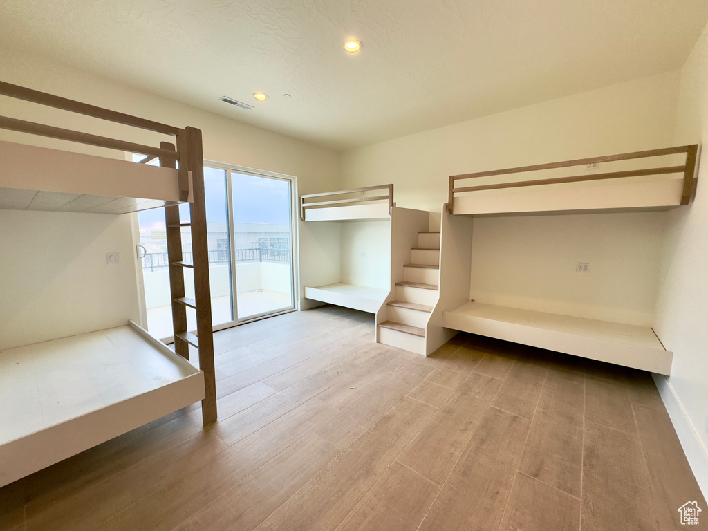 Unfurnished bedroom with access to exterior and hardwood / wood-style floors