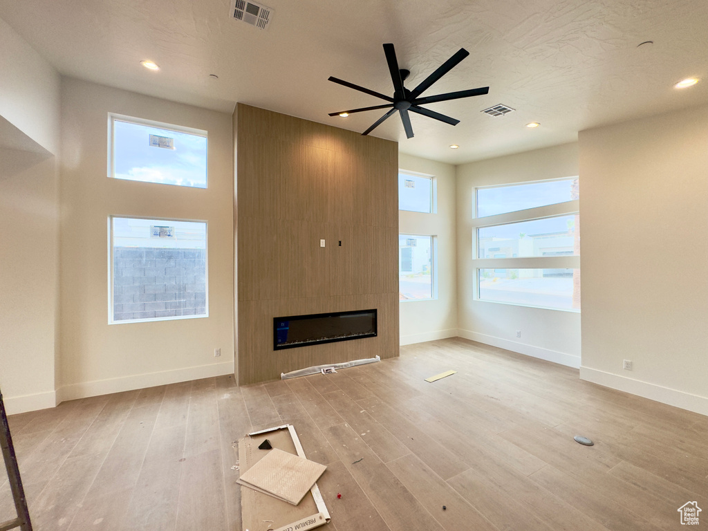 Unfurnished living room with a fireplace, light wood-type flooring, and ceiling fan