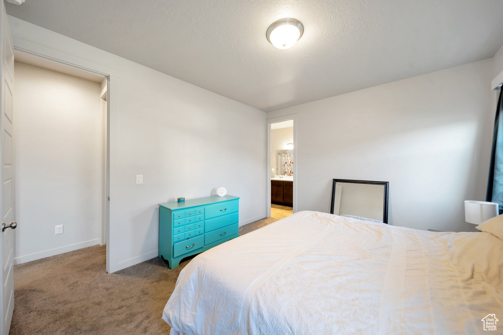 Bedroom featuring light colored carpet, a textured ceiling, and connected bathroom