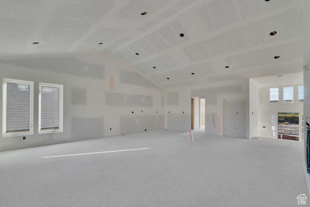 Carpeted empty room featuring high vaulted ceiling