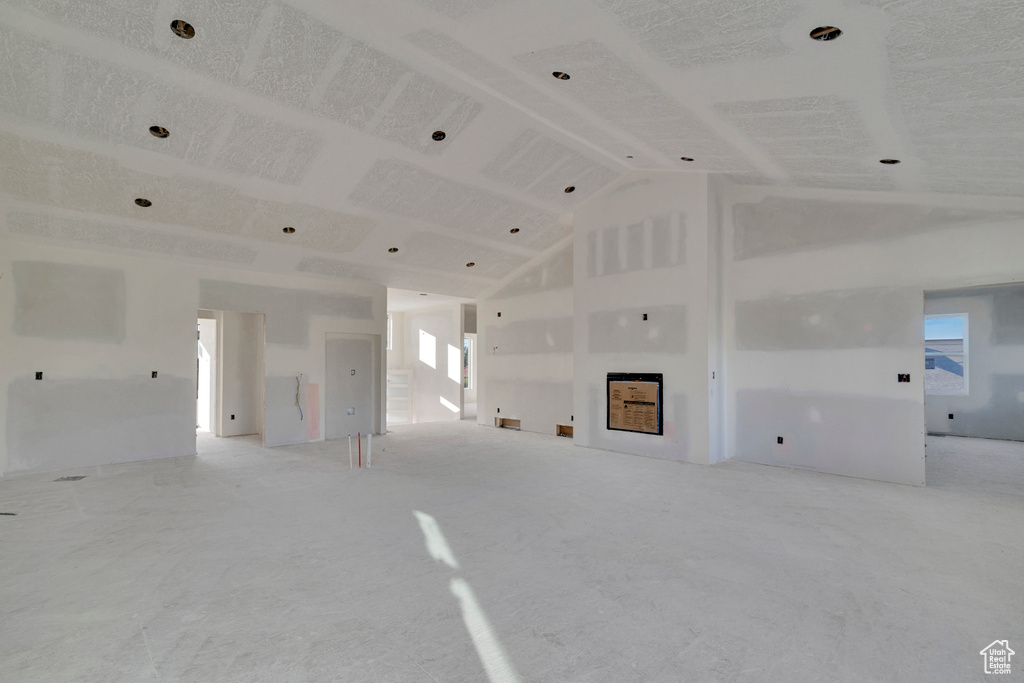 Unfurnished living room with high vaulted ceiling and a wealth of natural light